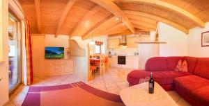 a living room with a red couch and a kitchen at Haus Sonnenseit'n in Neustift im Stubaital