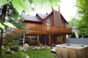 a large wooden house with a deck and a hot tub at Chalets Alpins- 4 Chemin des Montagnards in Stoneham