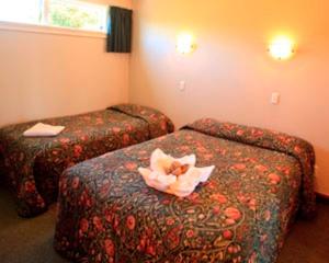 a hotel room with two beds with flowers on them at Blue Dolphin Motel in Timaru