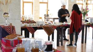 a man and a woman standing at a table with food at Taypikala Deluxe Valle Sagrado in Urubamba