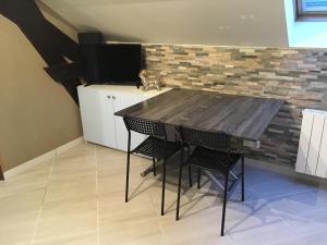 een tafel en stoelen in een keuken met een bakstenen muur bij Appart Hôtel l'Orchidée in Morangis