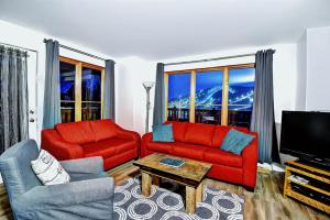 a living room with two red couches and a television at Chalets Alpins - 17 Chemin Alpin in Stoneham