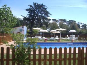 een zwembad met parasols, stoelen en tafels bij Villa Emilia, Terraces & Pool in Sant Martí d’Empúries