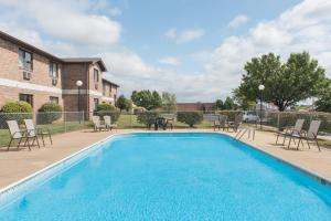 a swimming pool with chairs and a table next to a building at Super 8 by Wyndham Farmington in Farmington