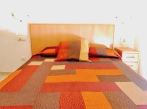 1 dormitorio con 1 cama grande y colcha colorida en Áticos Boutique Peñíscola en Peñíscola