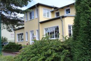 ein gelbes Haus mit weißen Fenstern in der Unterkunft Hotel Villa Strandkorb in Graal-Müritz