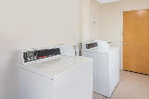 a kitchen with a microwave and a washer and dryer at Super 8 by Wyndham Farmington in Farmington
