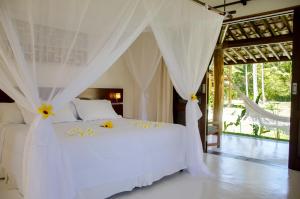 a bedroom with a white bed with white drapes at Villa dos Corais in Morro de São Paulo +37 photos