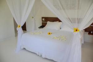 a bedroom with a white bed with flowers on it at Villa dos Corais in Morro de São Paulo