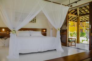a bedroom with a white bed with a canopy at Villa dos Corais in Morro de São Paulo