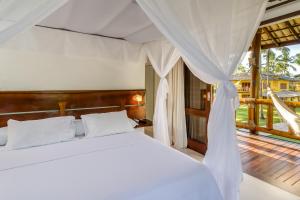 a bedroom with a white bed and a balcony at Villa dos Corais in Morro de São Paulo