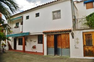 Casa Las Violetas في Altura: بيت أبيض بأبواب خشبية وساحة