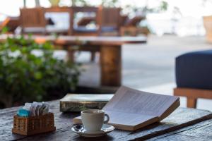 a book and a cup of coffee on a table at Villa dos Corais in Morro de São Paulo