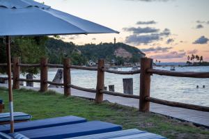 a fence on the beach with chairs and an umbrella at Villa dos Corais in Morro de São Paulo