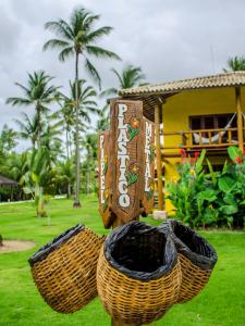 two baskets sitting in the grass in front of a house at Villa dos Corais in Morro de São Paulo
