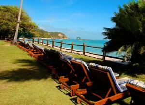 a row of chairs sitting on the grass near the ocean at Villa dos Corais in Morro de São Paulo