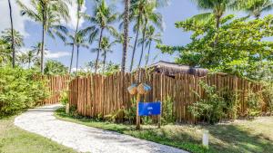 a wooden fence next to a path with palm trees at Villa dos Corais in Morro de São Paulo
