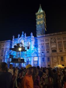 uma multidão de pessoas em frente a um edifício com uma torre de relógio em Guest House Hello Roma em Roma