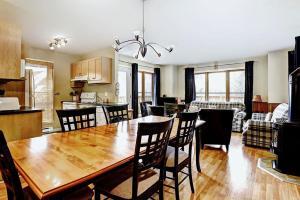 a kitchen and living room with a wooden table and chairs at Chalets Alpins 13 Chemin Alpin in Stoneham