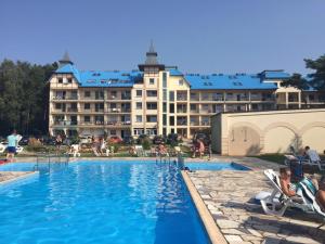 a hotel with a swimming pool in front of a building at Pati Ferien Apartmens in Łukęcin