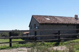 an old black barn with a fence in a field at Masia La Casablanca in La Puebla de Valverde
