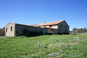 an old building sitting in a field next to a fence at Masia La Casablanca in La Puebla de Valverde