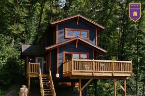 a cabin in the woods with a porch and a deck at Chalets Alpins -09 Chemin Alpin in Stoneham