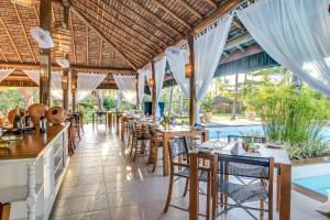 a restaurant with tables and chairs and a pool at Villa dos Corais in Morro de São Paulo