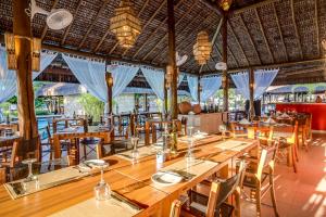 a restaurant with wooden tables and chairs and blue drapes at Villa dos Corais in Morro de São Paulo