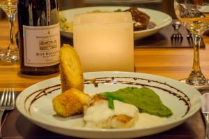 a plate of food on a table with a bottle of wine at Villa dos Corais in Morro de São Paulo