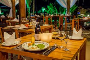 a wooden table with a plate of food and wine glasses at Villa dos Corais in Morro de São Paulo