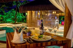a table with a plate of food and wine glasses at Villa dos Corais in Morro de São Paulo