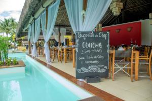 a restaurant with a sign next to a swimming pool at Villa dos Corais in Morro de São Paulo