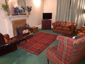 a living room with leather furniture and a fireplace at Rigg House B&B in Kirkconnel