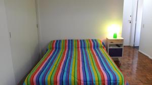 1 cama a rayas en una habitación con una lámpara sobre una mesa en Distrito Palermo Apartment en Buenos Aires