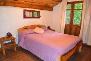 a bedroom with a bed with a purple comforter at Cabañas Las Moras in Tandil