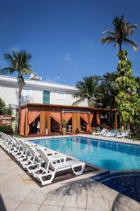 a swimming pool with lounge chairs next to a building at Hotel Vicino al Mare in Guarujá