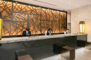 a lobby with three people sitting at a counter at Sotetsu Fresa Inn Kawasaki-Higashiguchi in Kawasaki