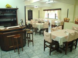 a restaurant with white tables and chairs and a piano at Hotel Mirante in Barra Velha