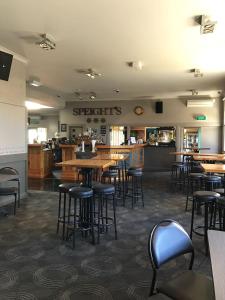 un comedor con mesas y taburetes en un restaurante en Otautau Hotel, en Otautau