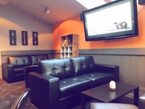 a waiting room with a leather couch and a screen at Otautau Hotel in Otautau