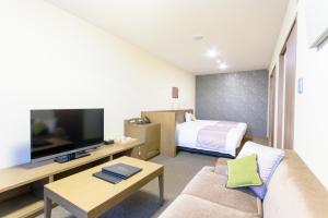 a living room with a couch and a tv and a bed at Isegekusando Iseshinsen in Ise