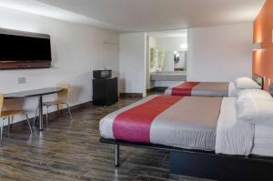 Habitación de hotel con 2 camas, mesa y TV. en Motel 6-Staunton, VA, en Staunton