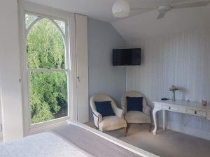 1 dormitorio con 2 sillas, escritorio y ventana en The Saddlery, en Greytown