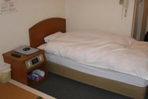 a bed in a room with a nightstand next to a bed sidx sidx sidx at Hiroshima Peace Hotel Ujina in Hiroshima