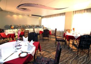 a dining room with tables and chairs with red table cloth at La Vinci Hotel in Dhaka