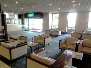 una sala de espera con sillas, mesas y ventanas en Yatsushiro Grand Hotel, en Yatsushiro