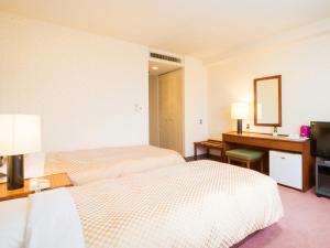 a hotel room with two beds and a desk at Yatsushiro Grand Hotel in Yatsushiro