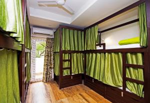 Habitación con cortinas verdes y literas. en Joey's Hostel Delhi en Nueva Delhi