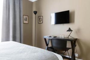 una camera da letto con scrivania e TV a parete di Hôtel Mathis Elysées a Parigi